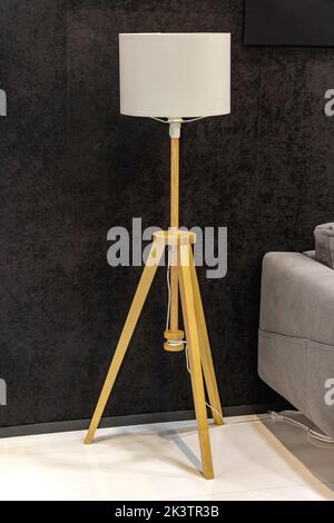 Modern Floor Lamp With Wooden Tripod Stand in Dark Home Stock Photo