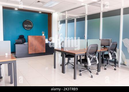 Interior of modern spacious workspace with comfortable chairs placed at coworking tables and reception desk with laptop Stock Photo