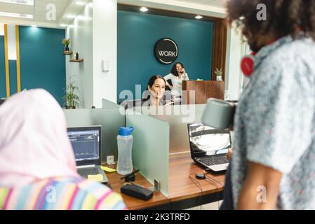 Group of multiracial coworkers sitting at table with laptops while working in contemporary office in Costa Rica in daylight Stock Photo
