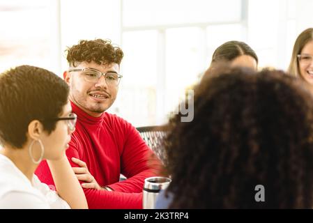 Group of multiethnic coworkers sitting at table and talking to each other about new business strategy during meeting in workspace in Costa Rica Stock Photo