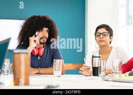 Focused multiracial female and male coworkers sitting at table in creative workspace and working on new startup project in Costa Rica Stock Photo