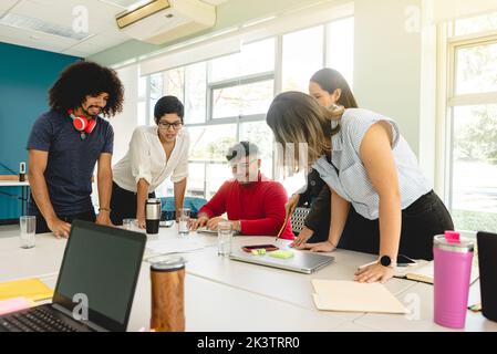Company of Hispanic coworkers gathering at table and analyzing new business project together during meeting in contemporary workspace in Costa Rica Stock Photo