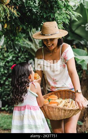 Woman and girl picking ripe star fruits from tree branches while spending time in orchard together Stock Photo