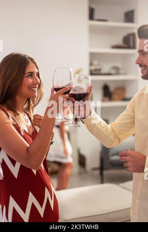 Cheerful young friendly couple drinking wine during party at home Stock Photo