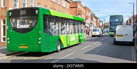 Public transport services traffic in sunny Witham town shopping street scene close up green First Essex single decker bus & double decker  England UK Stock Photo