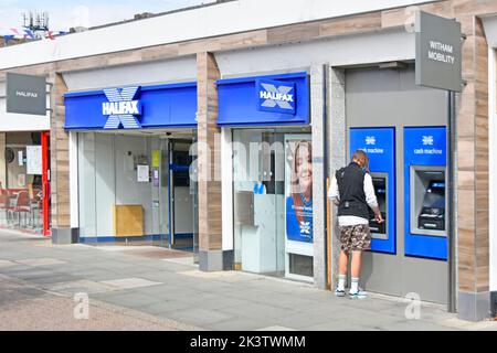 Façade Halifax Building Society now just Halifax & part of Lloyds Bank back view customer using one of two ATM cash machines Witham Essex England UK Stock Photo