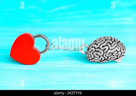 Red heart shaped padlock chained to a human brain isolated on blue background. Stock Photo