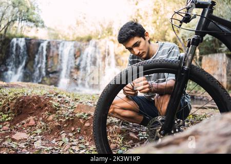 Male cyclist fixing mechanism of bicycle against hiker setting in forest Stock Photo