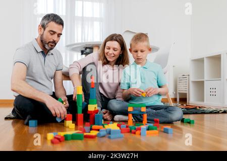 Cheerful parents with children playing with module blocks while playing in light house room Stock Photo