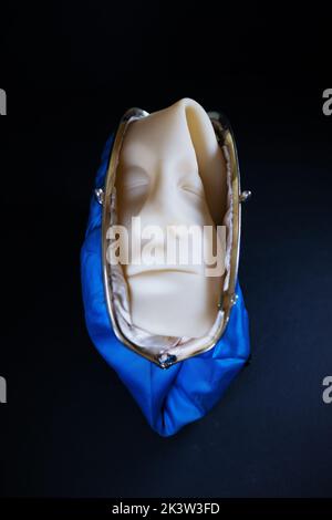 A squished rubber face squeezed into a blue clutch purse. Stock Photo