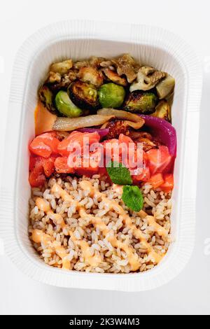 Poke with brown rice, salmon and grilled vegetables in a plastic takeout container Stock Photo