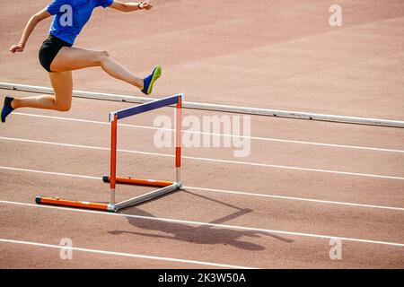 female athlete hurdling at stadium Stock Photo