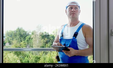 attractive Construction worker makes notes in tablet. service man installing window. High quality photo Stock Photo