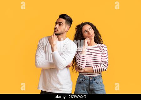 Thoughtful Arab Young Man And Woman Standing Over Yellow Studio Background Stock Photo