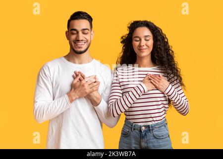 Thank You. Grateful Young Arab Man And Woman Keeping Hands On Chest Stock Photo