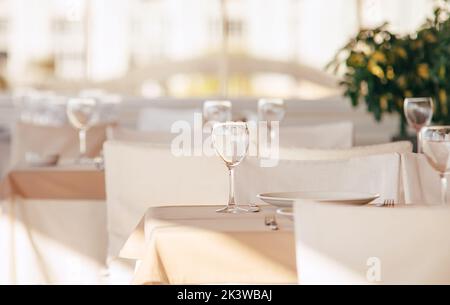 Empty wine glass standing on the table tablecloth. Luxury white colors restaurant indoor shot. Stock Photo