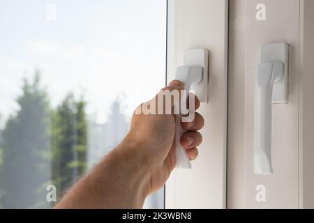 Male hand opens modern plastic window, first person view Stock Photo