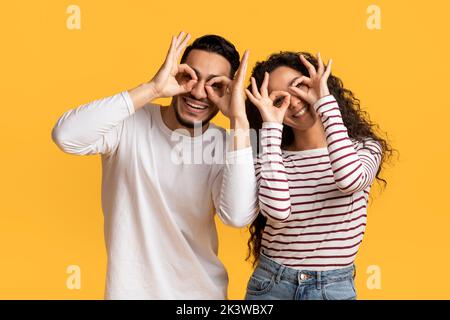 Cheerful middle eastern couple making funny glasses with fingers Stock Photo