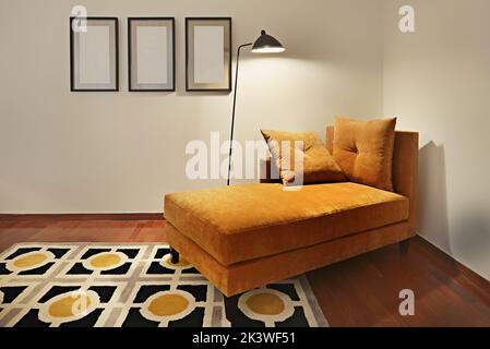 Ocher velvet divan with a rug in matching shades in an area dedicated to reading Stock Photo