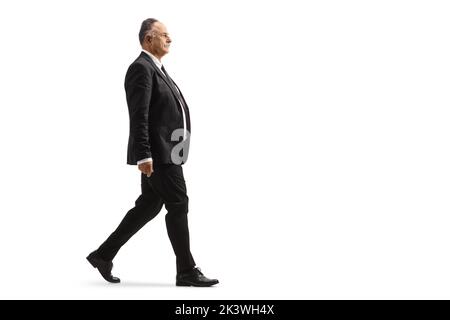 Full length profile shot of a mature businessman in a black suit walking isolated on white background Stock Photo