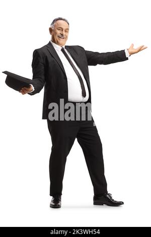 Cheerful mature man in black suit and tie dancing and holding a hat isolated on white background Stock Photo