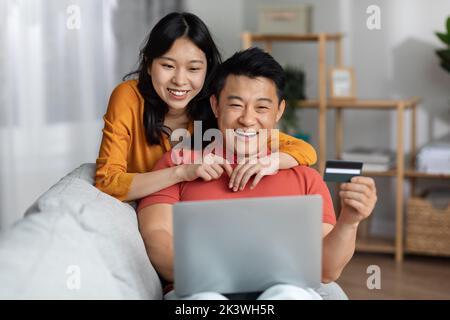 Happy asian spouses using notebook and credit card Stock Photo
