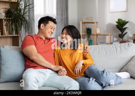 Happy korean spouses sitting on couch at home Stock Photo