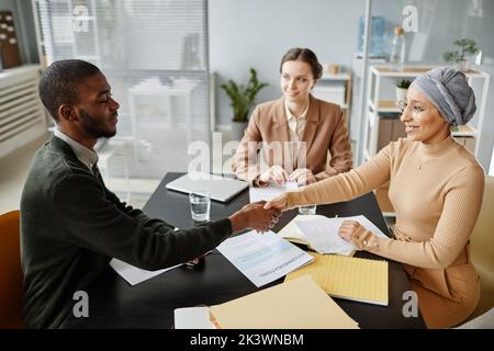 High angle view at diverse group of people in job interview shaking hands with candidate and smiling Stock Photo