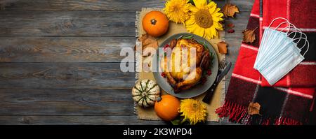 Roasted chicken or turkey for Thanksgiving Day, red blanket, autumn decorations, protective mask, top view. Concept Thanksgiving in pandemic covid, ce Stock Photo