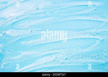 Liquid gel cosmetic on blue. Texture of blue gel or sanitizer. Pattern of transparent gel for face cleansing. Moisturizing cosmetic beauty product for Stock Photo