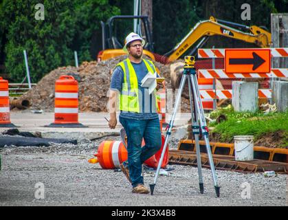 2022 05 13 Tulsa, OK USA - Surveyer calling out to someone on construction site with book in his hand by tripod with Optical Leve Stock Photo