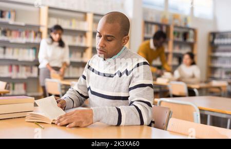Young adult man studying in public library Stock Photo