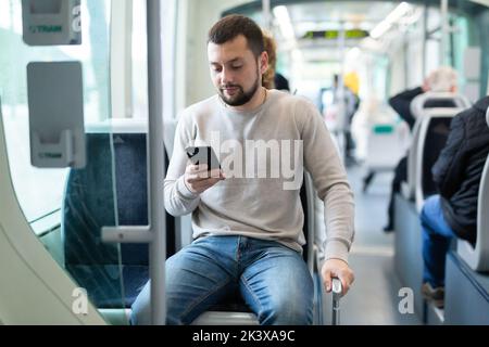 Portrait of european man standing in tram carriage and using phone Stock Photo