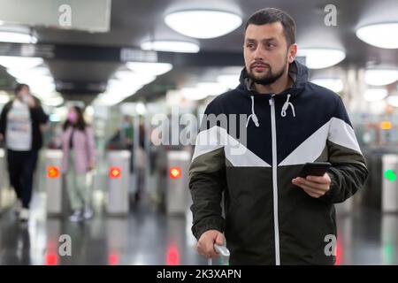 Man in jacket with a mobile phone near turnstile in subway Stock Photo