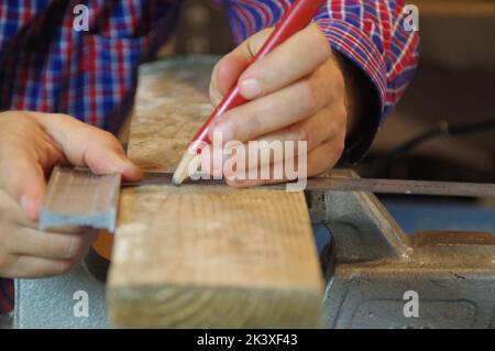 Carpenter in the workshop prepares a cutting raw board. Joiner worker in carpentry shop. A thorough expert and careful craftsman focused on work. Stock Photo