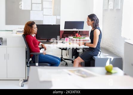 Creatives in action. two female colleagues talking at a desk in an office. Stock Photo