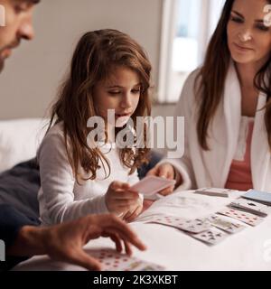 Playing her best cards. a young family playing cards together at home. Stock Photo