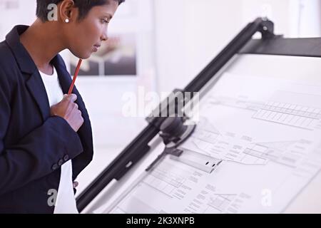 Waiting for some inspiration. a female architect working at a drawing board. Stock Photo