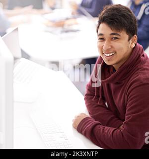When all else fails a programmer wont. Portrait of a happy young man working on his computer in an office. Stock Photo