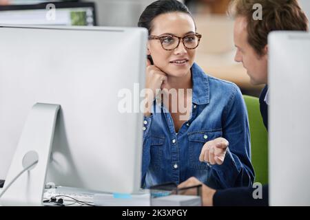 Taking time out to talk it over. Tow colleagues having a discussion at a desk. Stock Photo