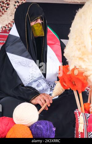 Masked Arab Woman from Abu Dhabi Wearing an Abaya, Putting Wool on to a Spindle. Stock Photo