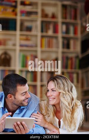 Planning their next romantic getaway. a young couple sitting at home using a digital tablet. Stock Photo