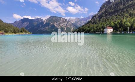 A gorgeous view of Lake Plansee in Tyrol, Austria with tall mountains ...