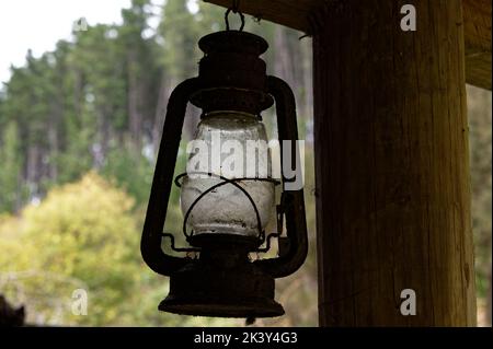 A metal vintage lamp needs a clean, it is hanging from a wooden beam. Stock Photo