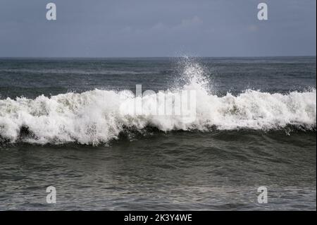 The frothing white of a wave face as it beaks and tumbles to the beach Stock Photo