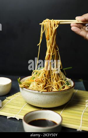 Noodles in bowl with chopsticks soya sauce and spring onions Stock Photo