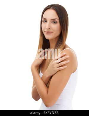 The picture of innocence. A young woman standing against a white background with her arms folded over her chest. Stock Photo
