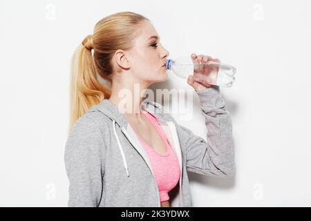 Keep hydrated. Studio shot of a young woman in exercise clothing drinking from a water bottle. Stock Photo