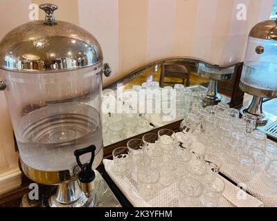 A glass transparent tank with a tap with cold drinking water stands in the hotel lobby. Close-up. Stock Photo