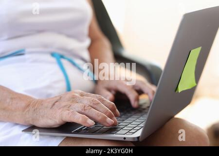 Hands of elderly woman typing on laptop keyboard closeup Stock Photo